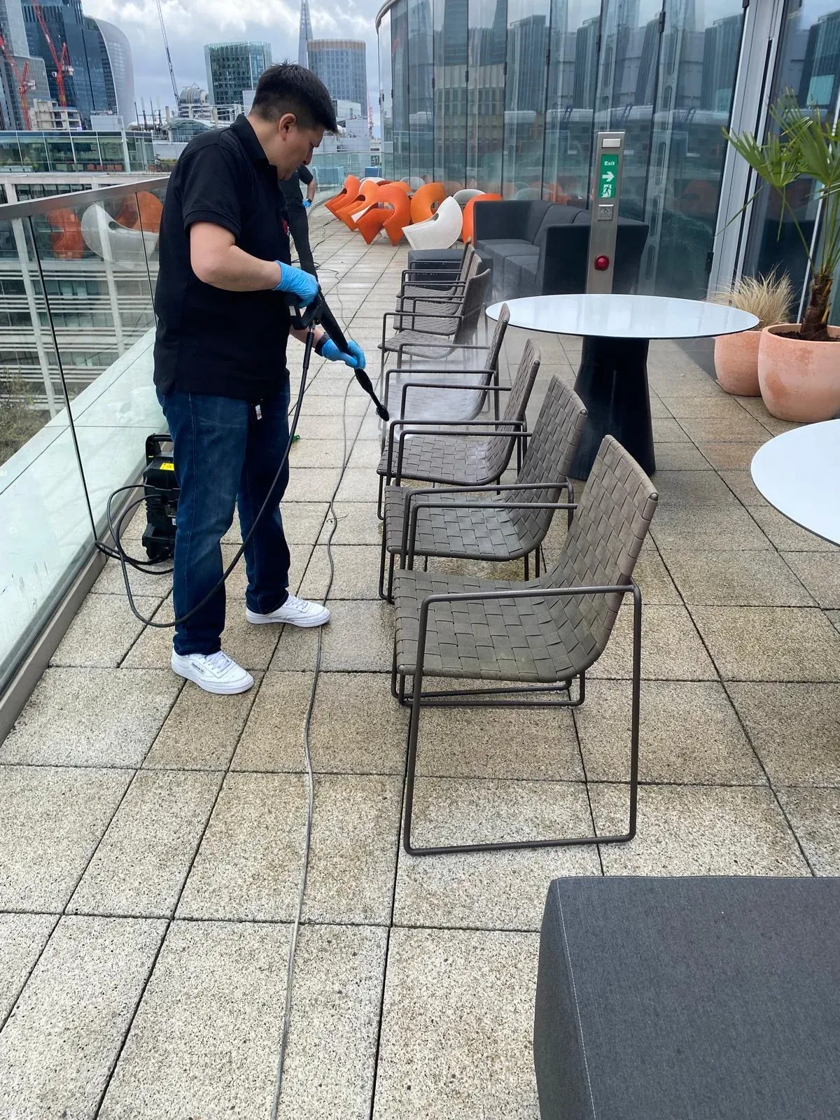 An operative pressure washing terrace chairs, Moorgate, London